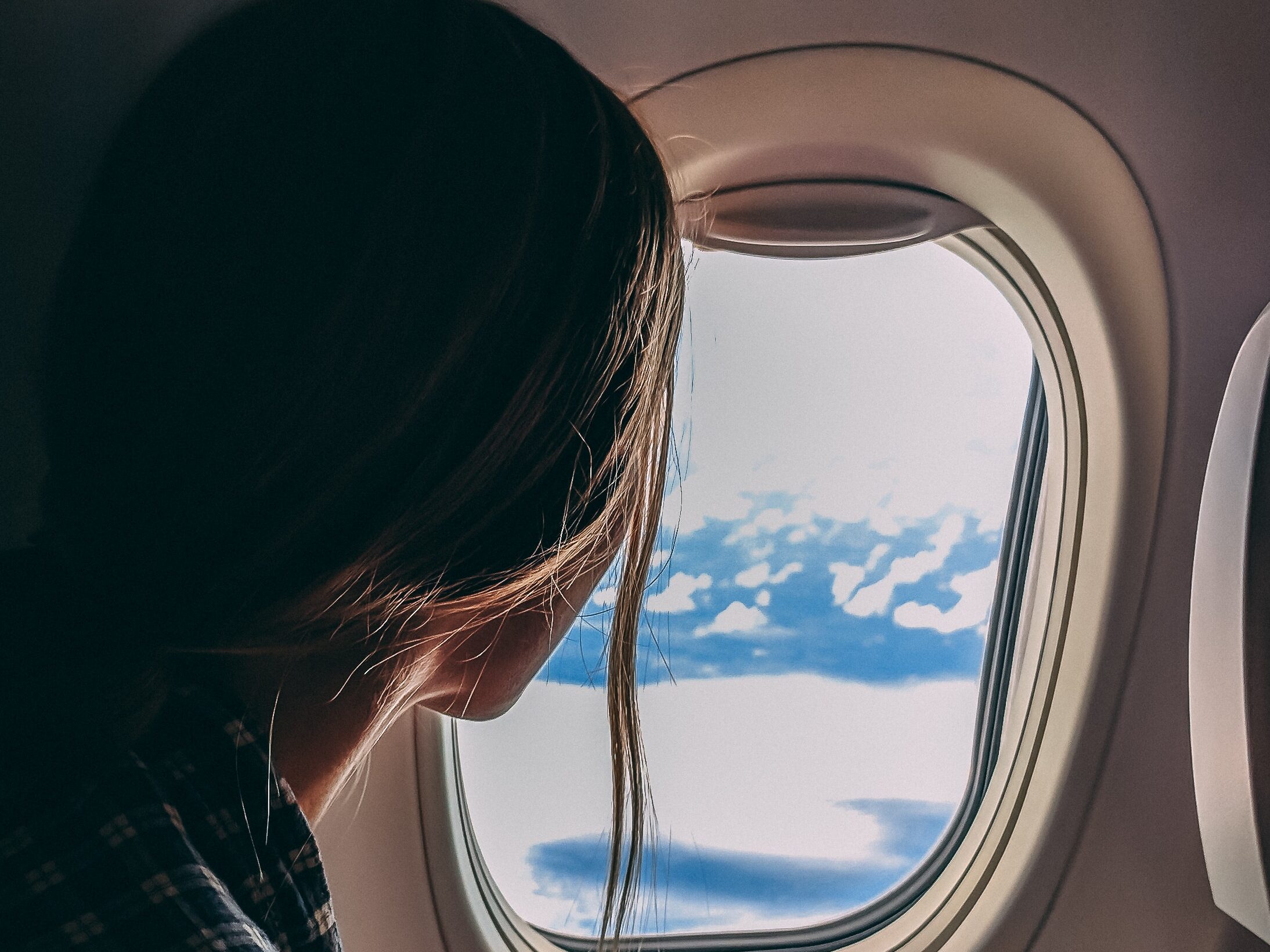 woman looking out of an airplane window