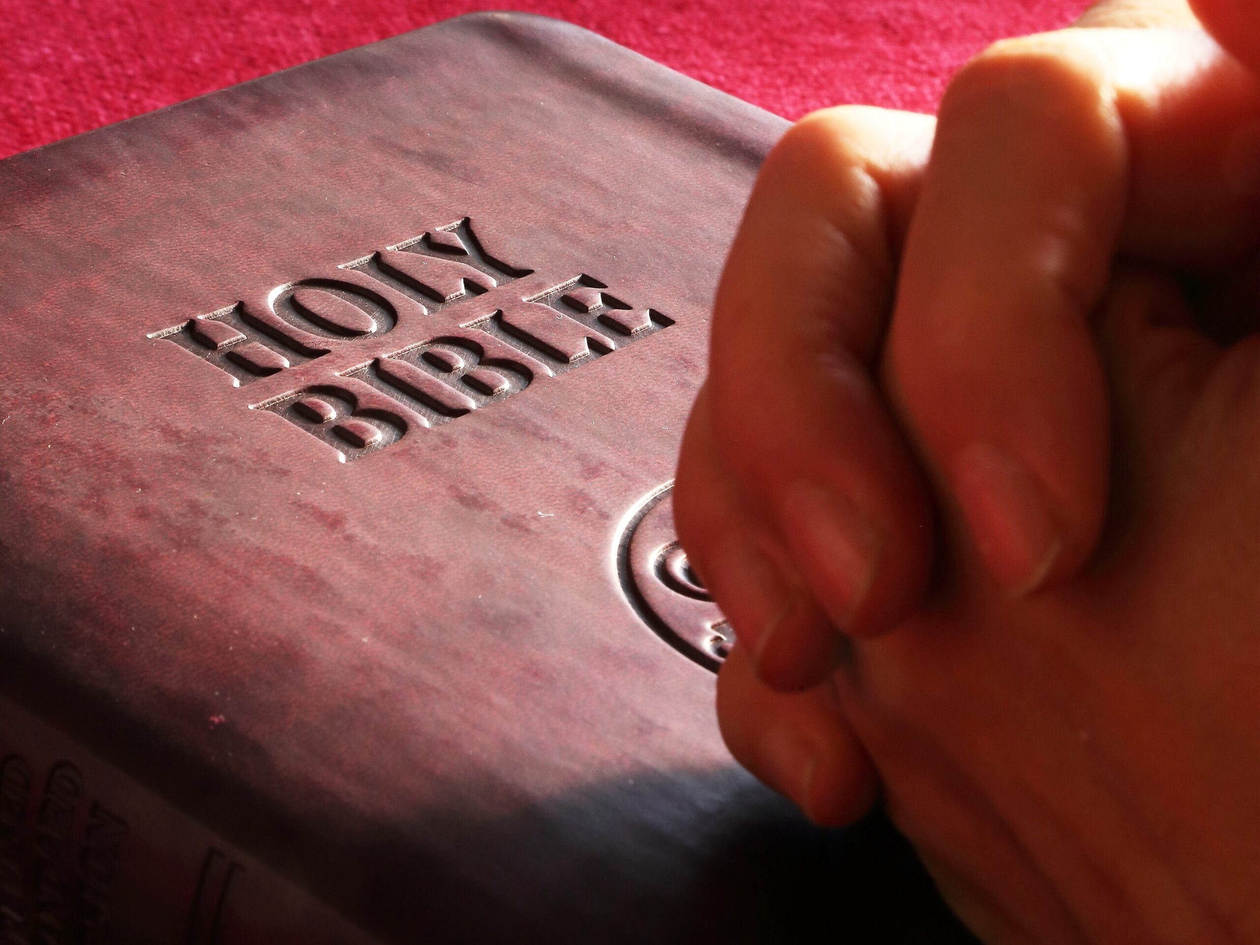 hands praying over holly bible